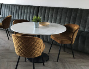 Dining bench combined with white round tables and ochre chairs in Dutch canteen